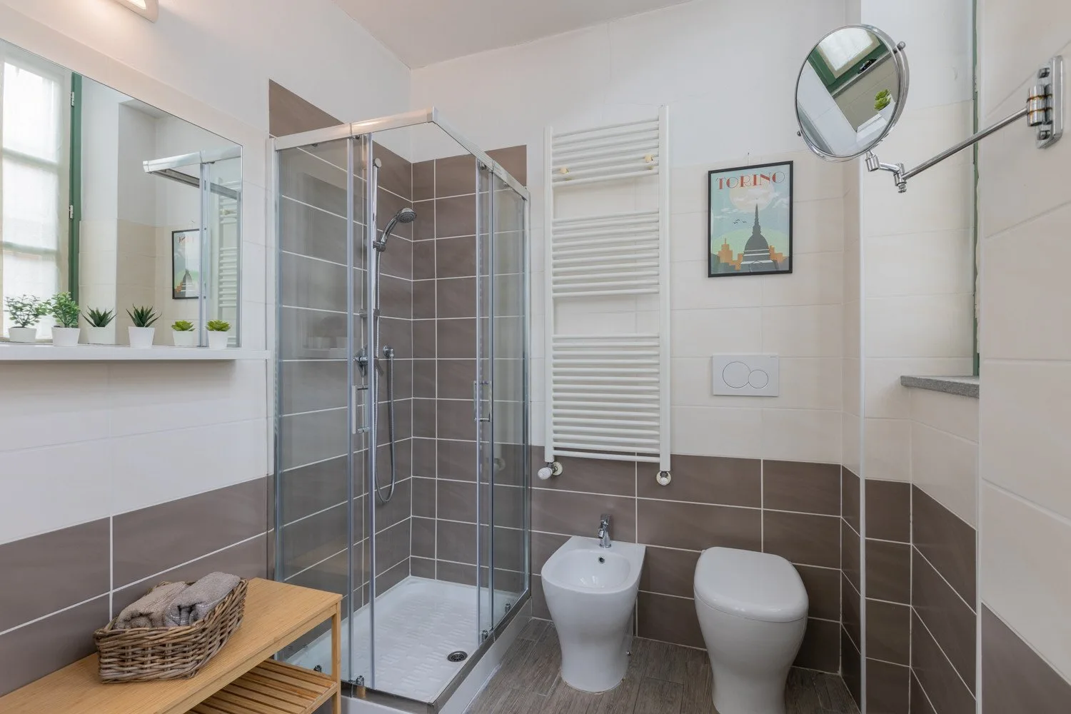 Un baño luminoso con ducha de vidrio, lavabo e inodoro.