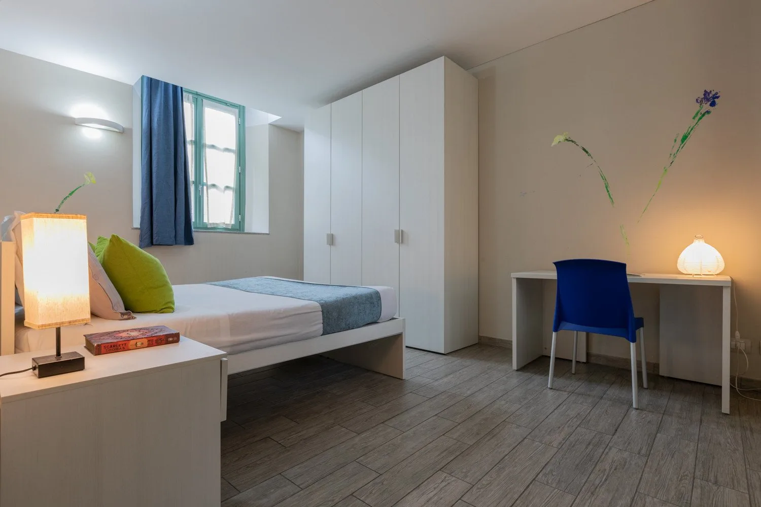 Un dormitorio con una cama, un armario y un escritorio junto a una ventana.