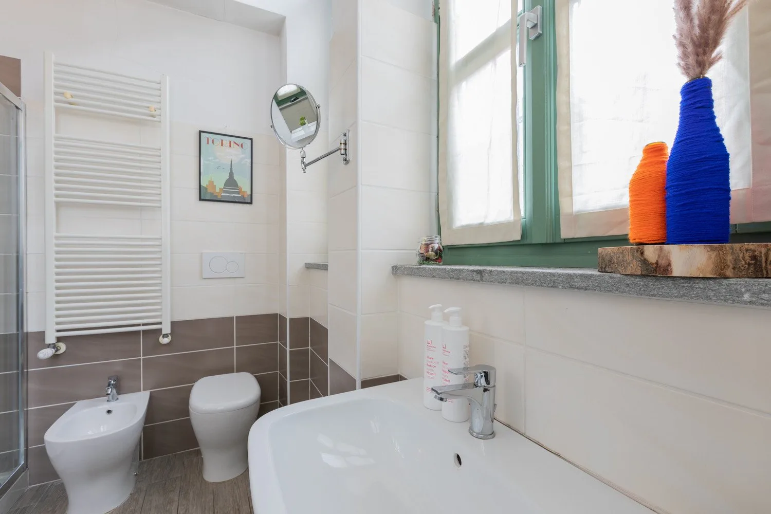 Un baño luminoso con una bañera bajo una ventana y un inodoro cerca.