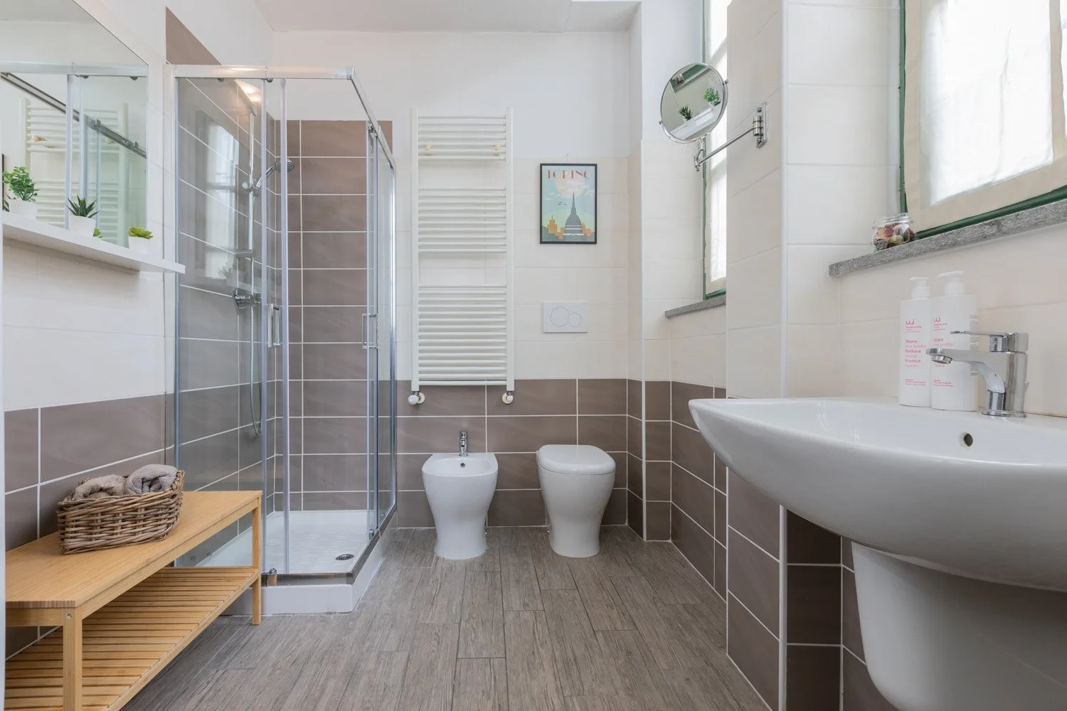 Un baño luminoso con ducha de vidrio, bañera y accesorios blancos.