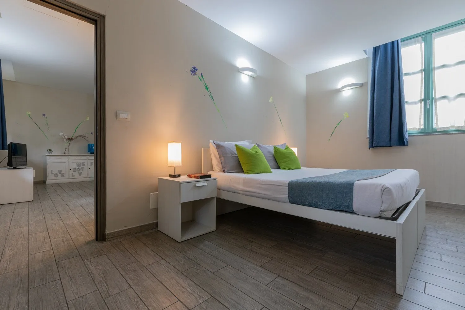 Un dormitorio con una cama, una mesita de noche y una ventana con cortinas azules.