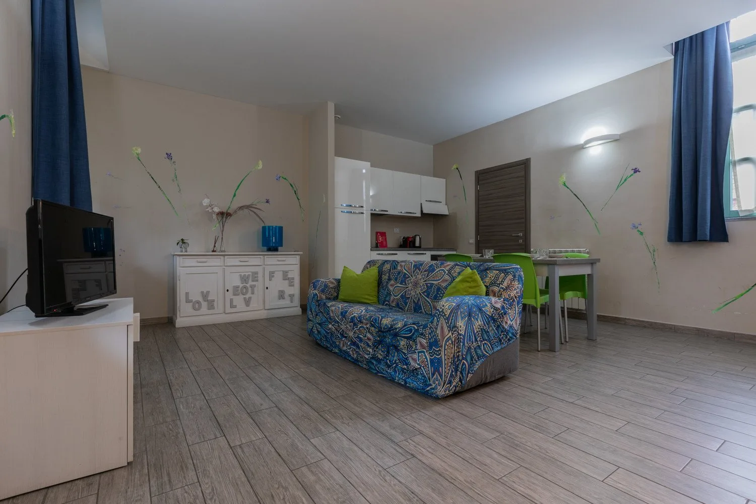 Una sala de estar con asientos estampados, un televisor y una mesa de comedor.