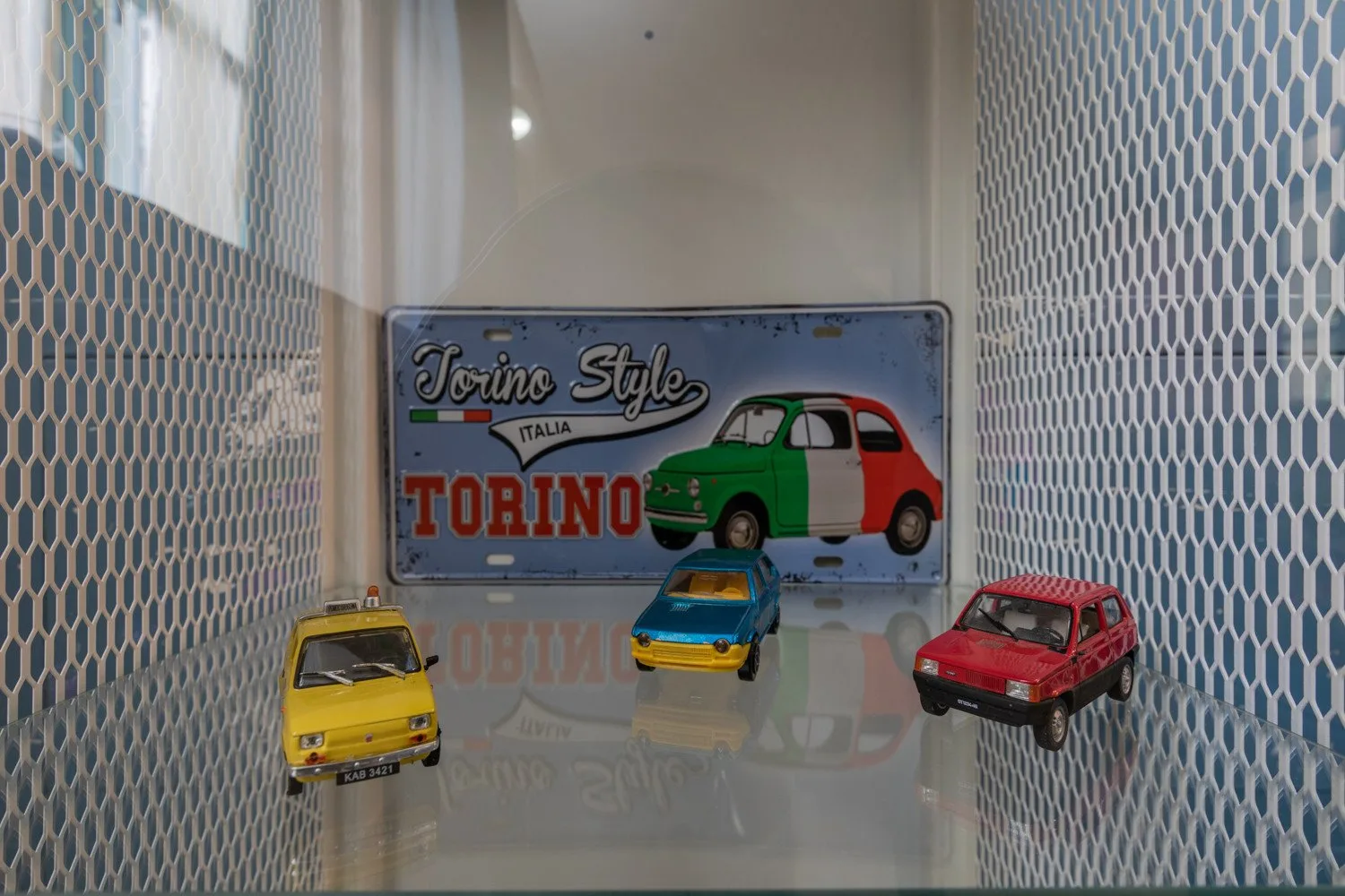 Una exhibición de coches en miniatura está entre paredes de azulejos estampados.