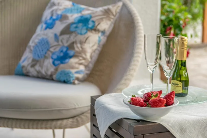 Una zona de estar en un patio con un cojín floral y un cuenco de fresas sobre la mesa.