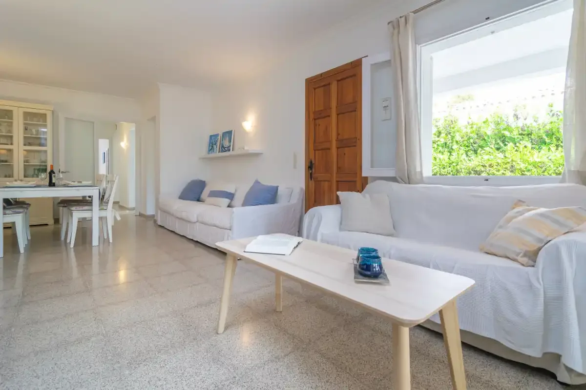 Una sala luminosa con asientos blancos y un comedor.