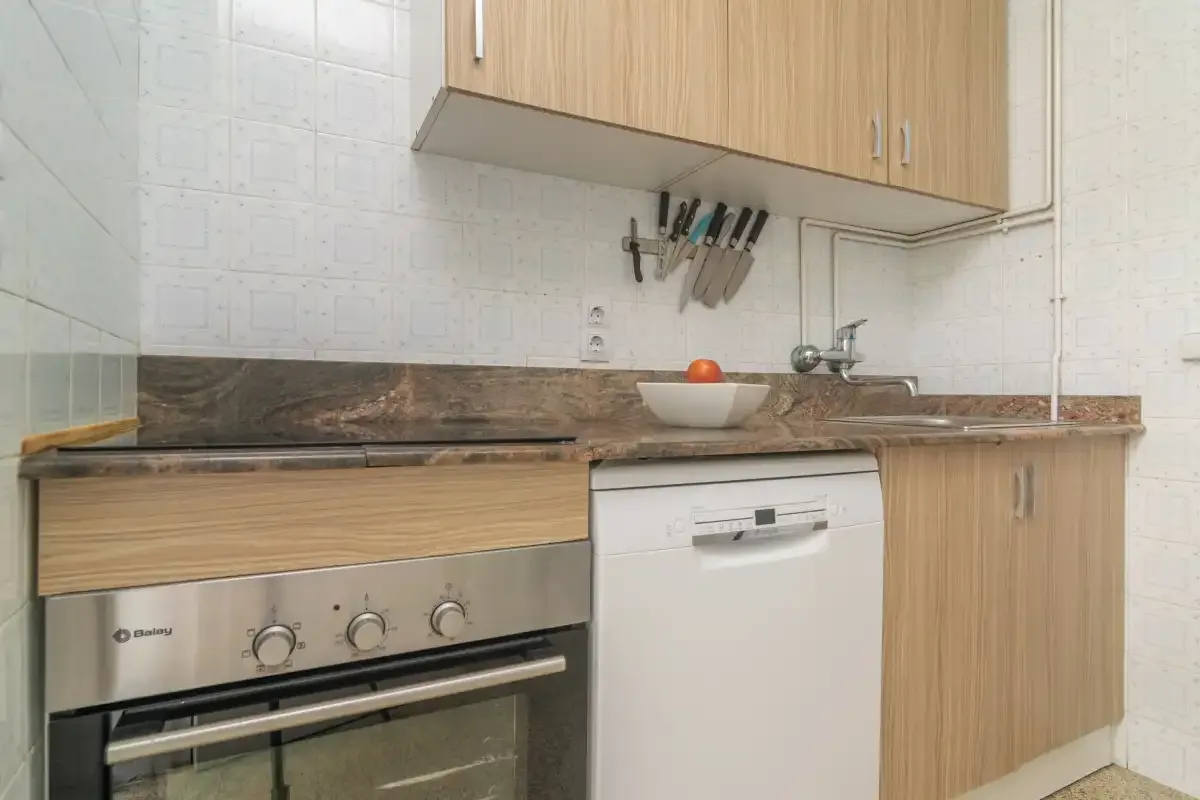 Una cocina con encimera, fregadero y horno empotrado.