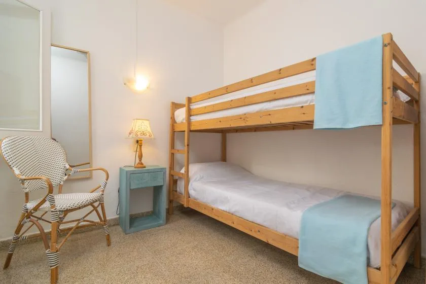 Un dormitorio con literas de madera y una silla pequeña al lado.
