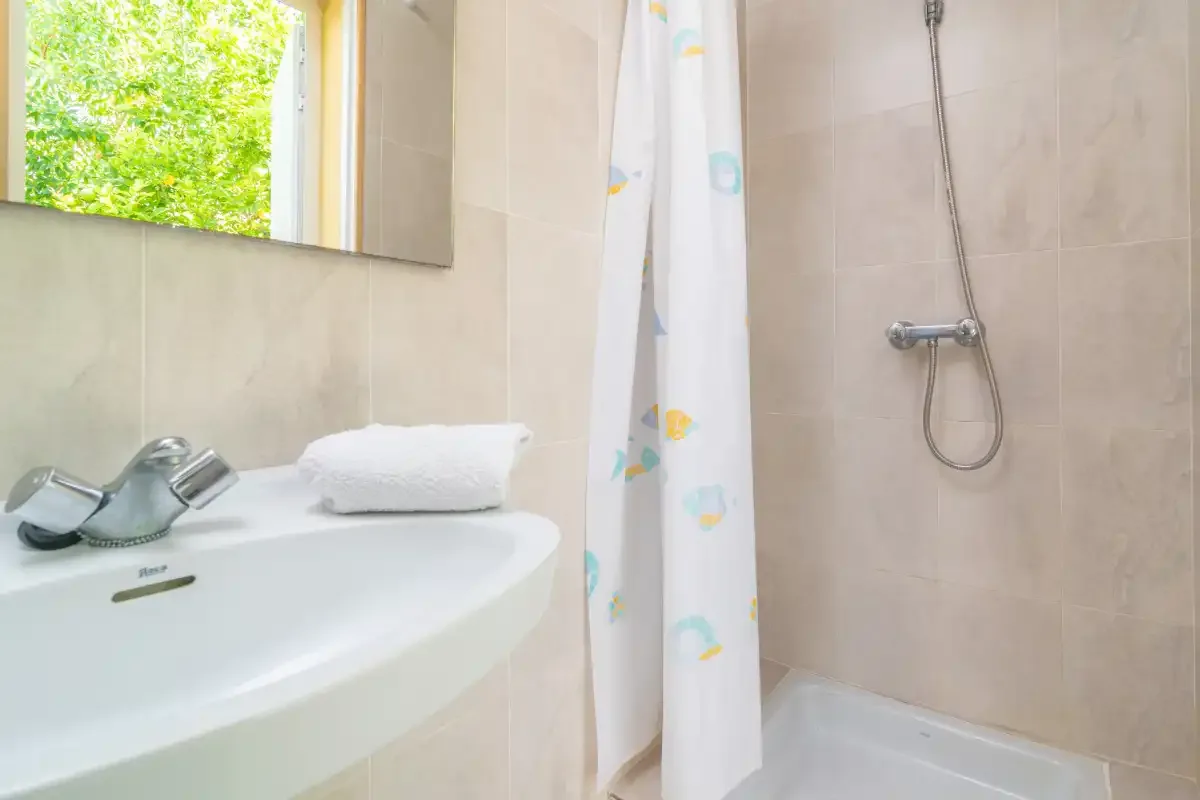 Un baño con lavabo, espejo y ducha.