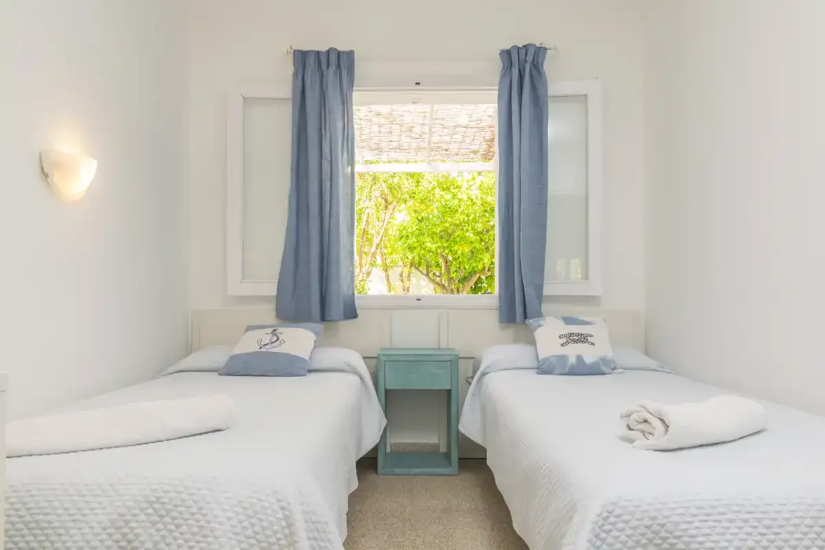 Un dormitorio luminoso con dos camas individuales junto a una ventana.