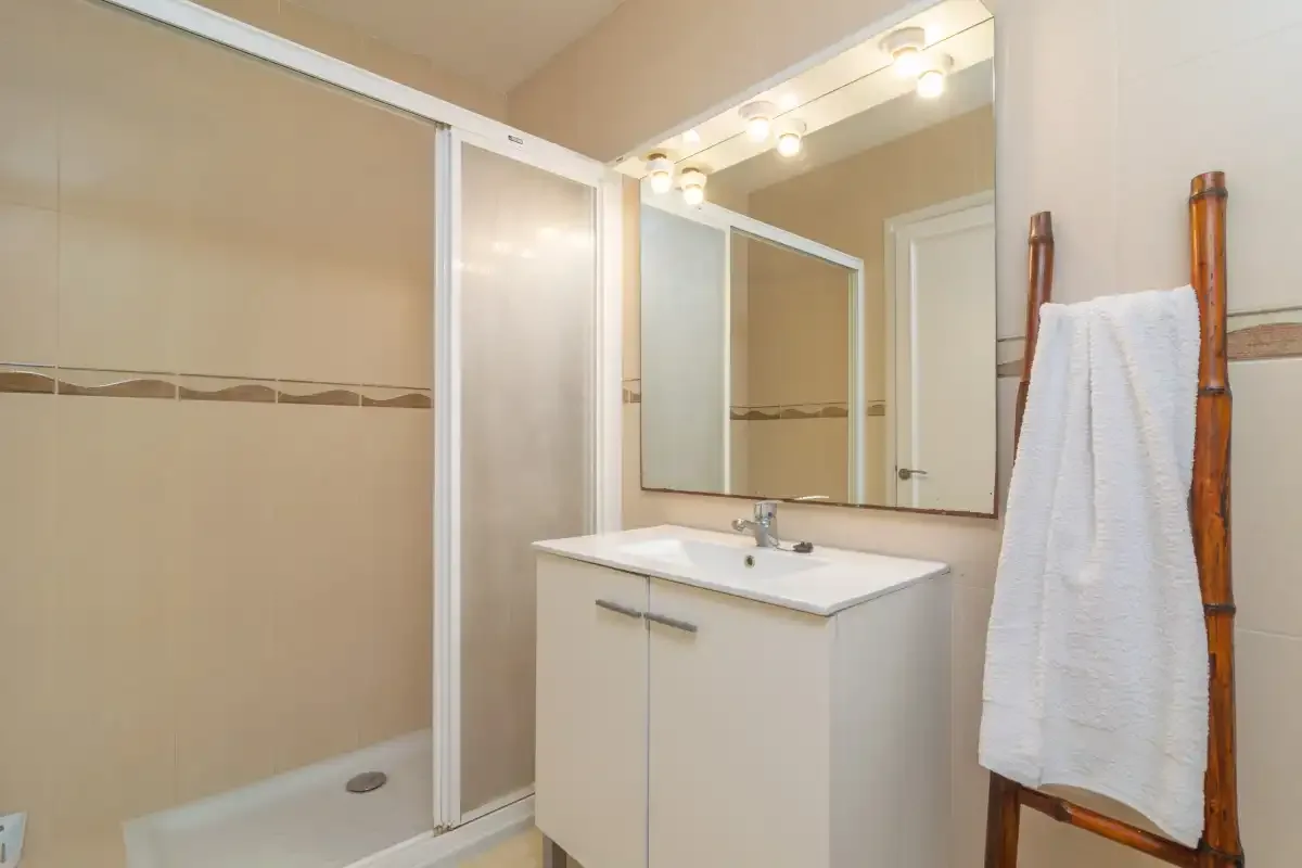 Un baño con lavabo, espejo y ducha de vidrio.