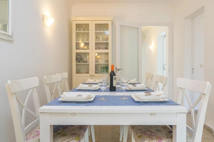 Un comedor con la mesa puesta y un aparador con puertas de cristal.
