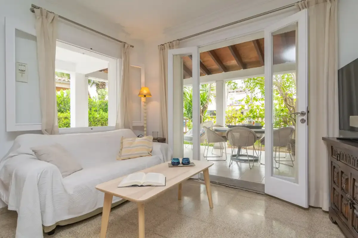 Una sala luminosa se abre a un patio cubierto con asientos al aire libre.
