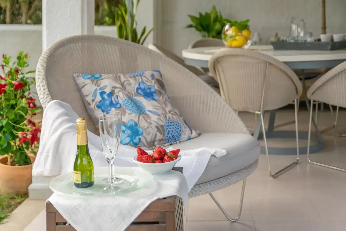 Una luminosa zona de estar en el patio con una mesita junto a plantas en macetas.