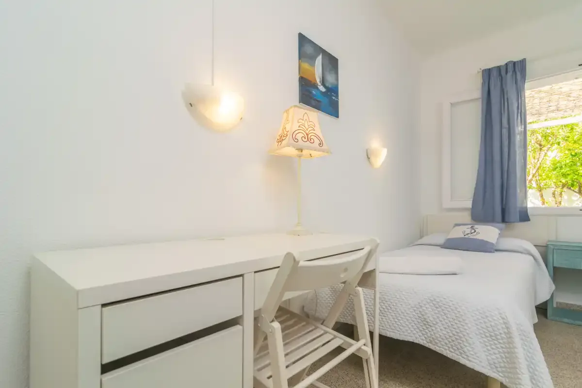 Un dormitorio con una cama individual junto a un escritorio y una silla.