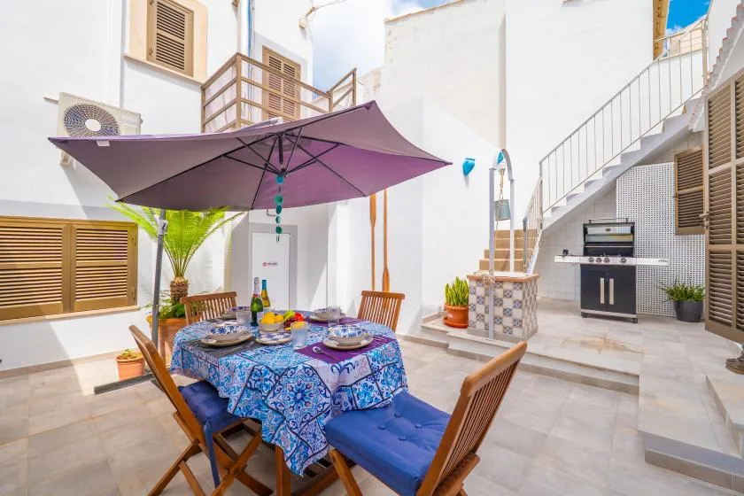 Una zona de comedor al aire libre con una mesa bajo una gran sombrilla morada.