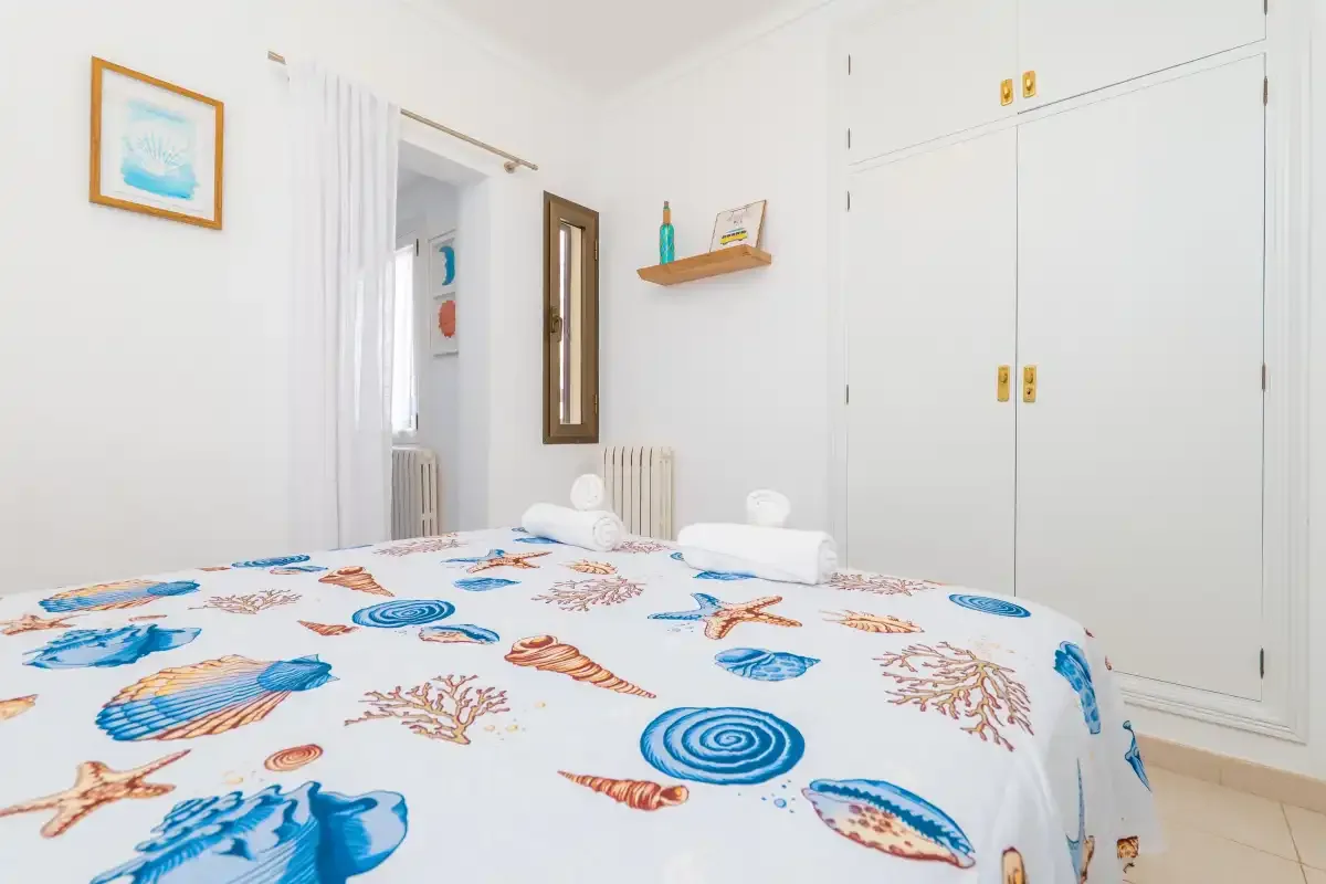 Un dormitorio con una cama cubierta de motivos marinos azules y naranjas.