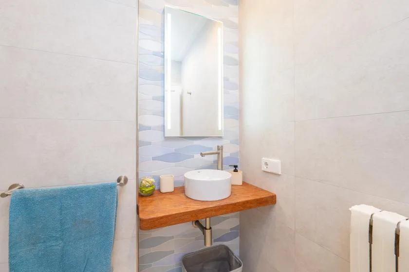 Un lavabo de baño con azulejos, espejo y toalla azul.