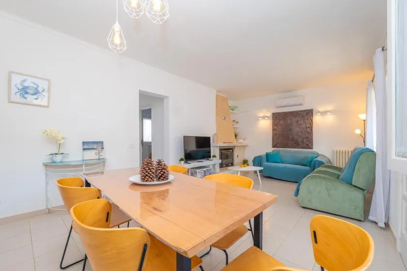 Una luminosa sala de estar y comedor con una mesa de madera y asientos coloridos.
