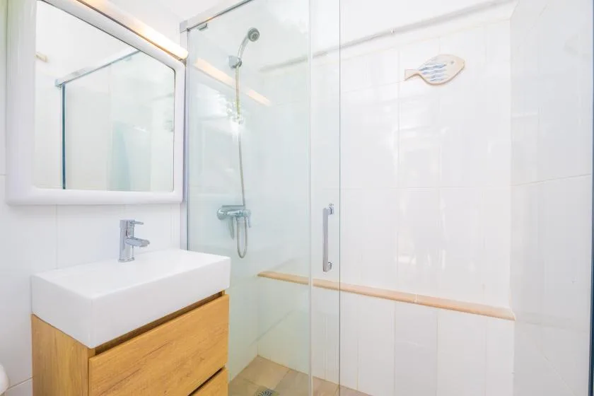 Un baño luminoso con lavabo, espejo y ducha de vidrio.