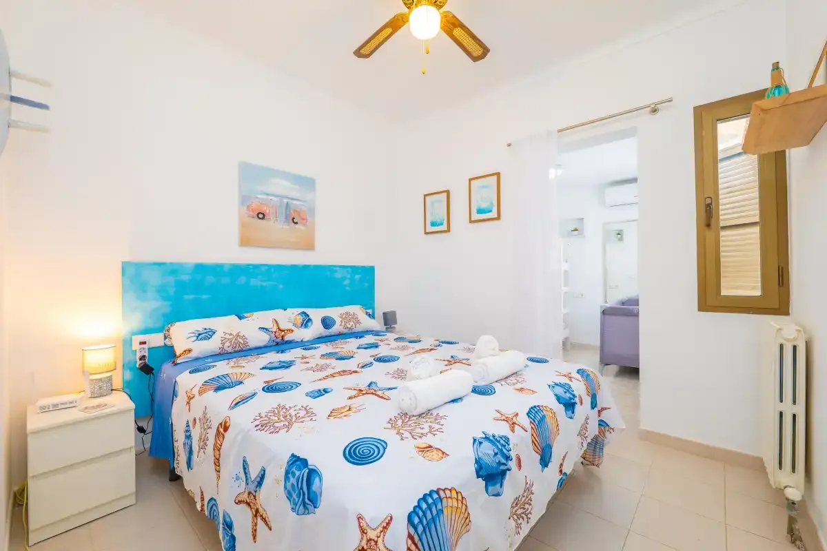 Un dormitorio con una cama grande y ropa de cama con estampado de conchas de colores.