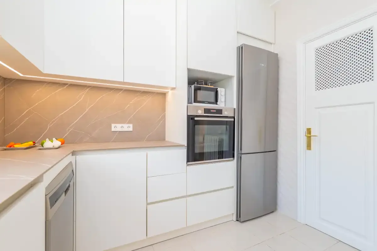 Una cocina moderna con armarios blancos y electrodomésticos integrados.