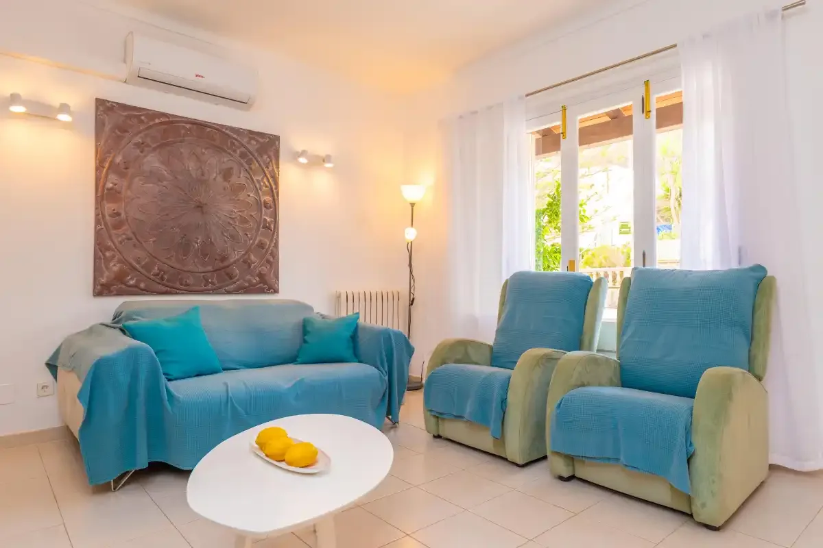 Un salón luminoso con asientos azules y una mesa de centro redonda.
