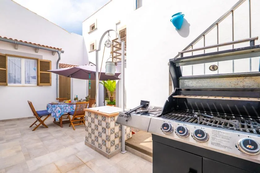 Un patio al aire libre con una mesa de comedor y una barbacoa abierta.