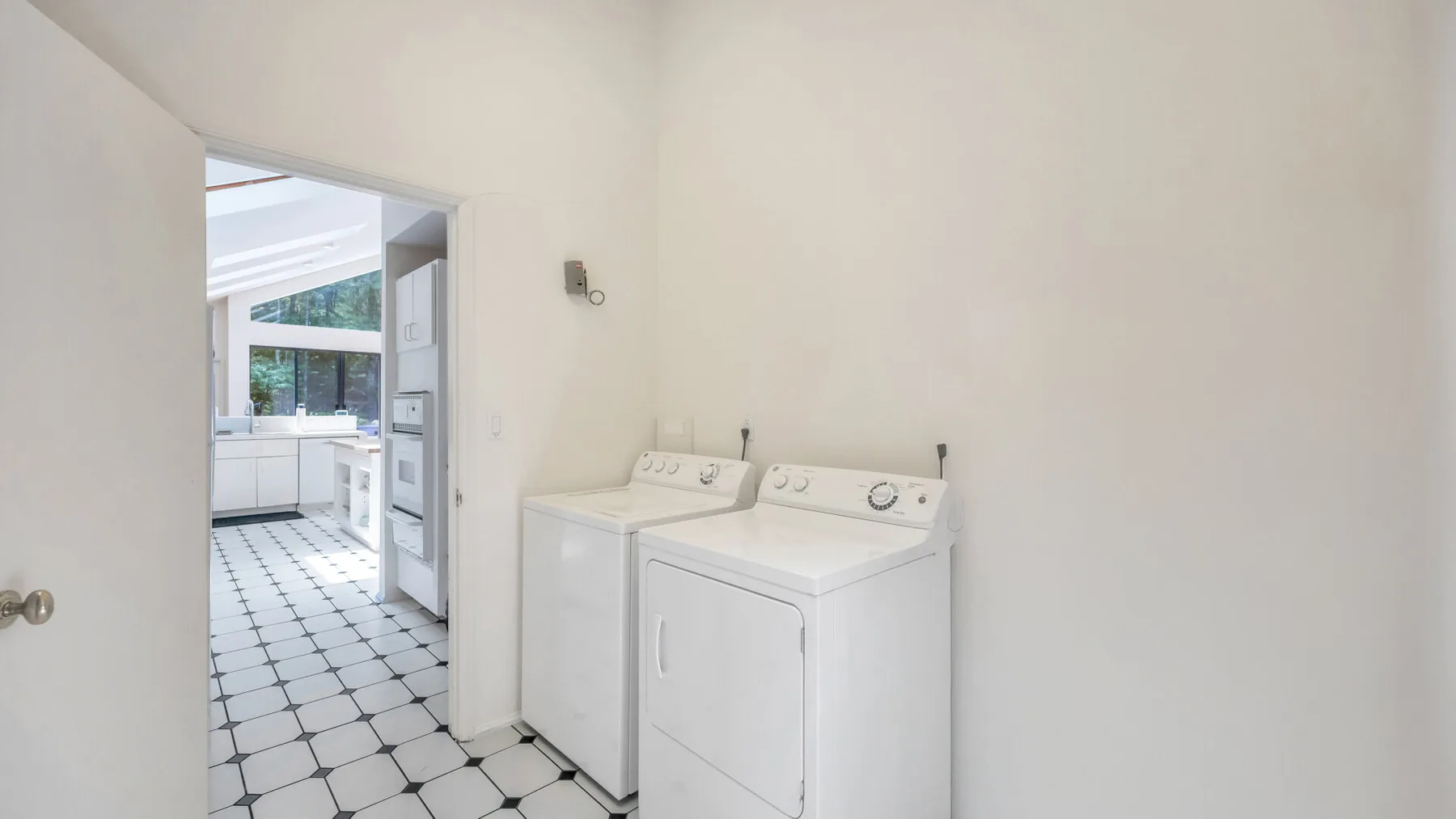 Un cuarto de lavandería con lavadora y secadora junto a una puerta abierta.