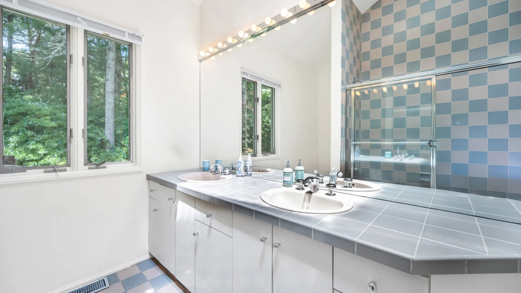 Un baño luminoso con un tocador largo, lavabos y ventanas amplias.
