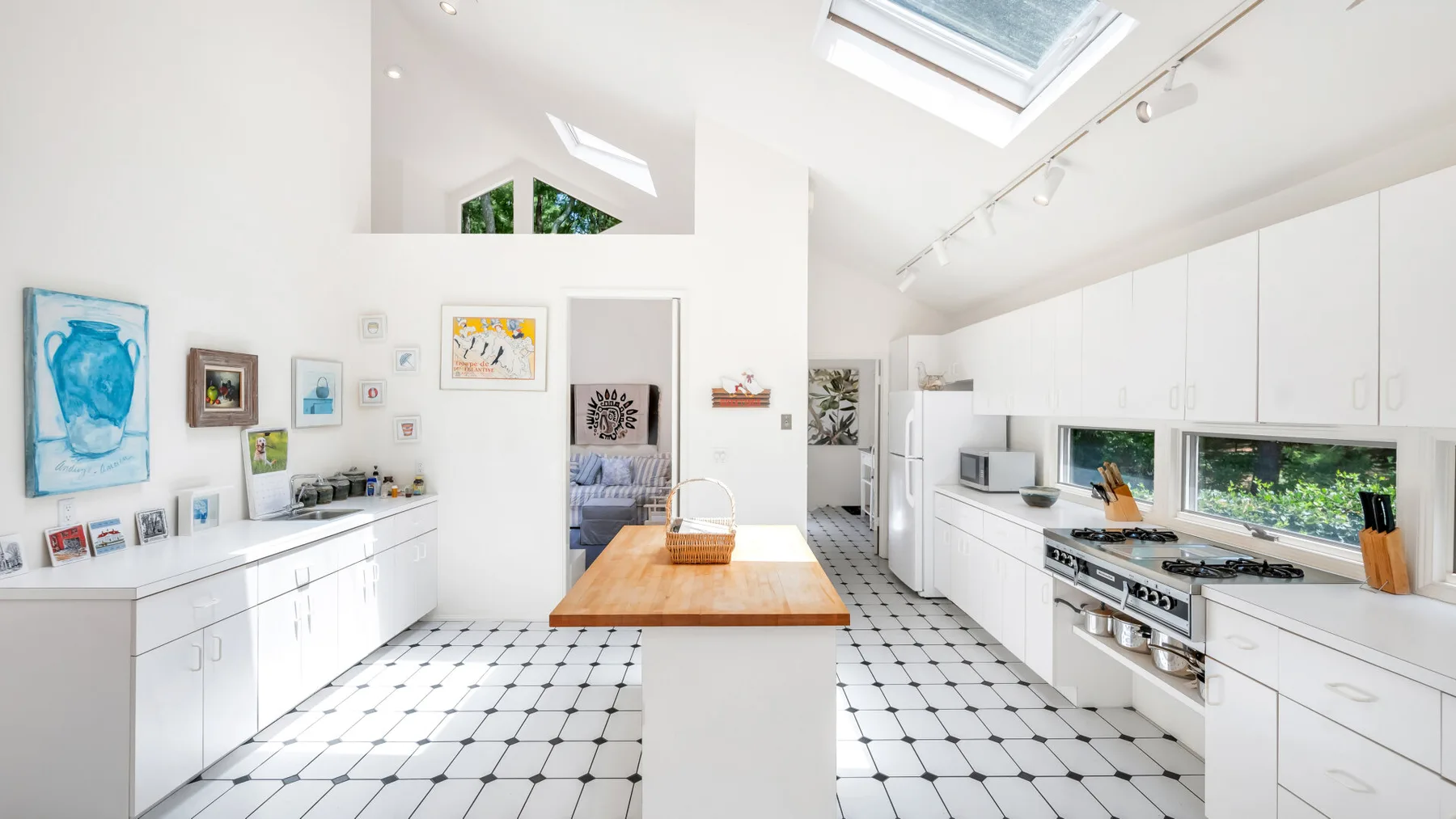 Una cocina blanca y luminosa con una isla de madera y tragaluces.