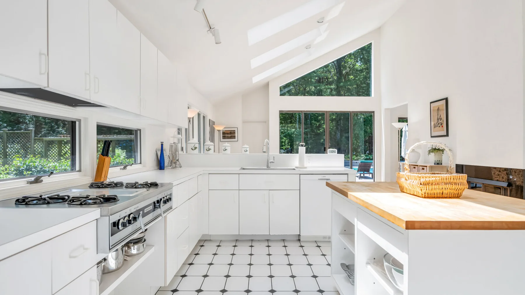 Una cocina blanca y luminosa tiene una encimera larga y una isla central.