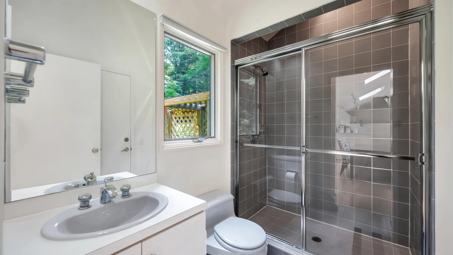 Un baño con lavabo y una ducha con mampara de vidrio.