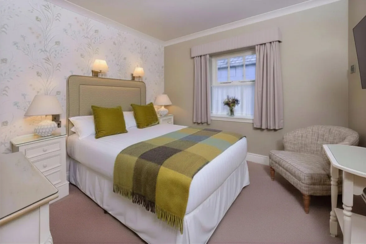 Double guest room with a neatly made bed and plaid blanket.