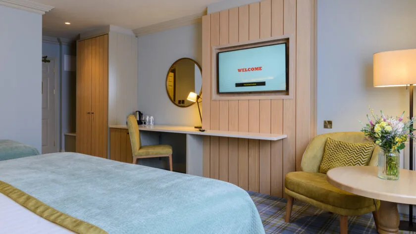 Modern guest room with a bed, desk and chair.