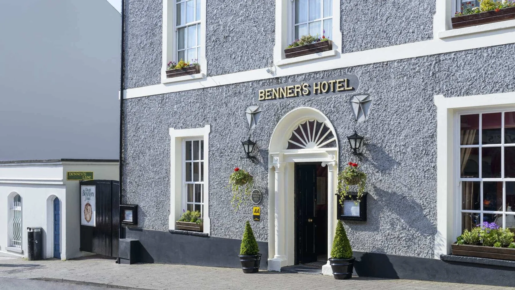Benners Hotel exterior entrance with potted plants and hanging flower baskets.