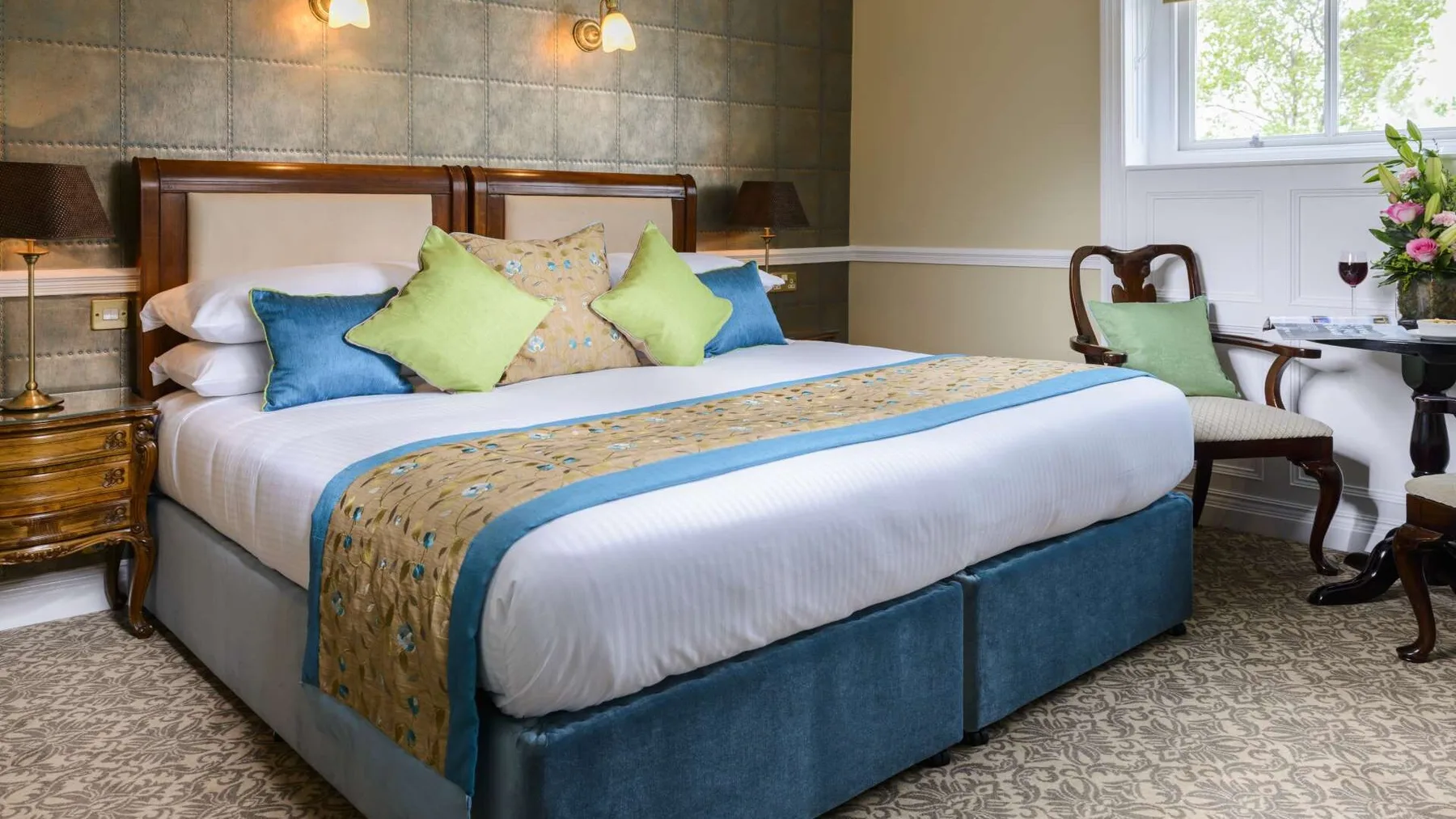 Superior guest room with a bed, chair and window overlooking greenery.
