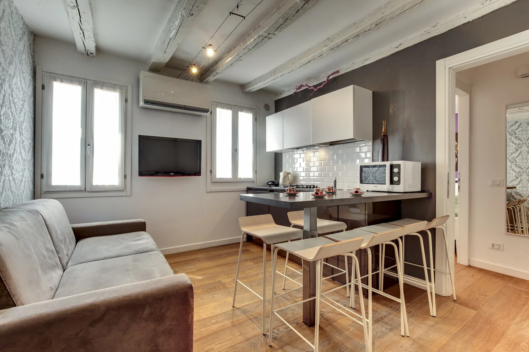 Una sala de estar con cocina, sofá, mesa de comedor y asientos de barra.