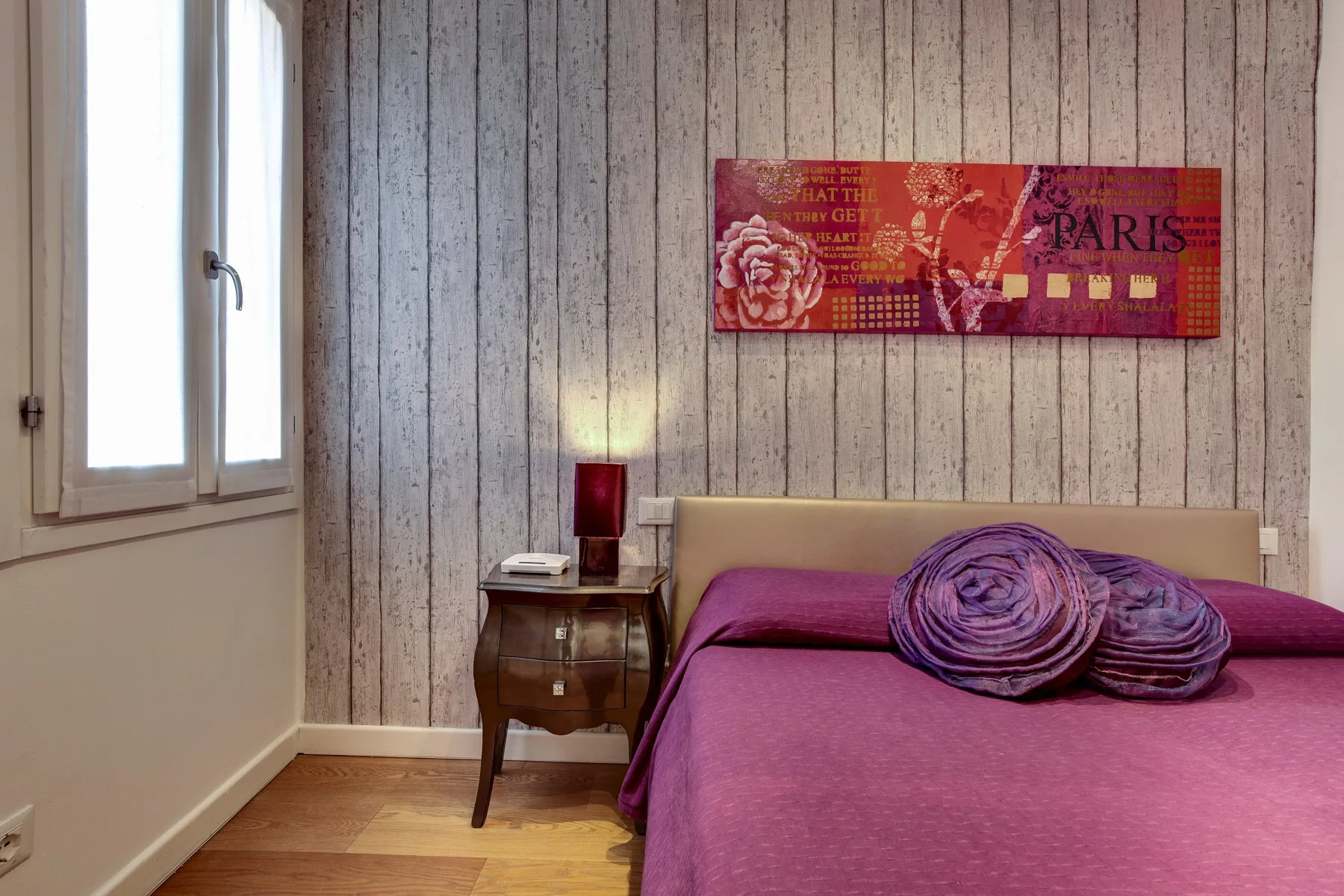 Un dormitorio con una cama morada junto a una ventana.