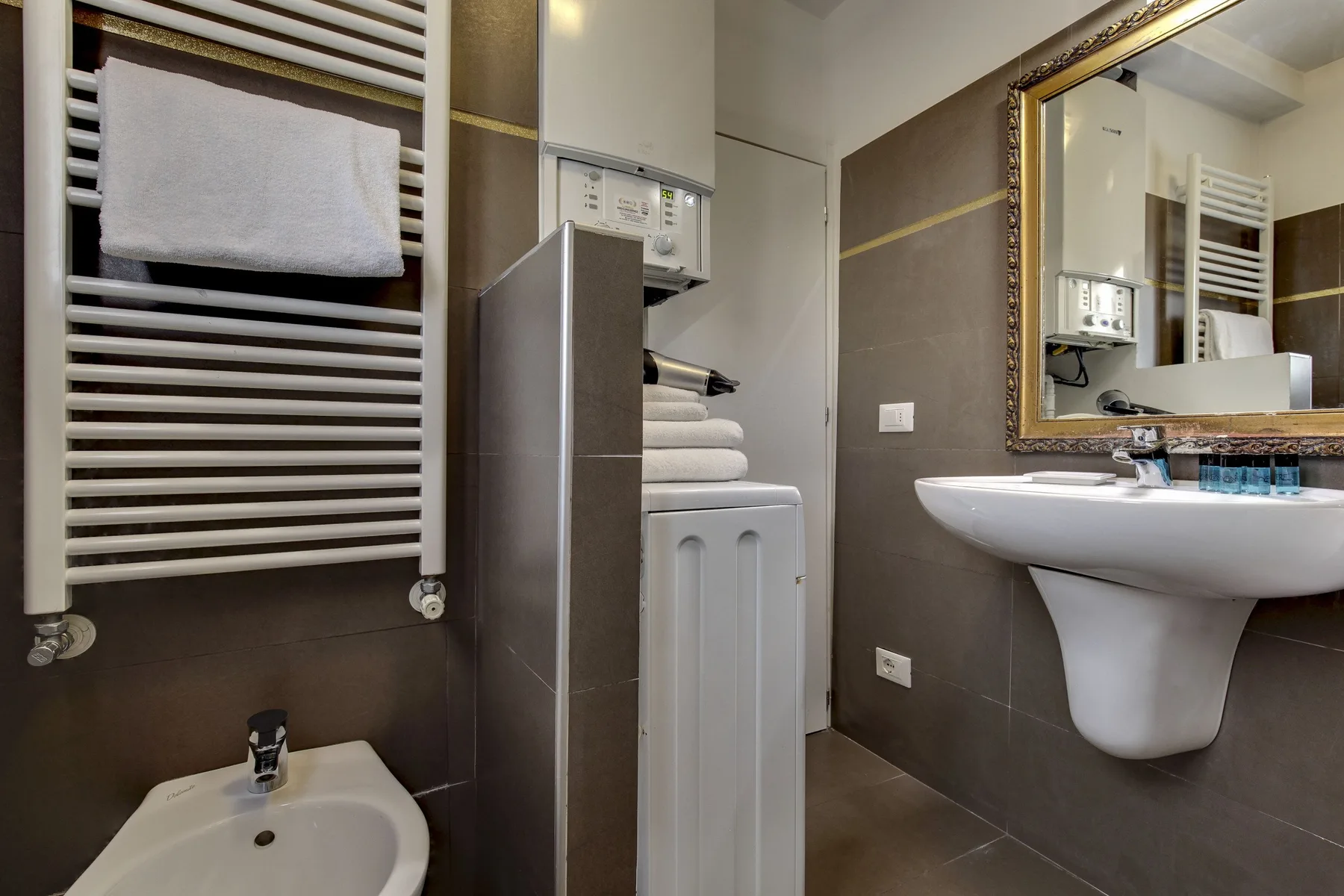 Un baño con lavabo de pared y toallero calefactable.