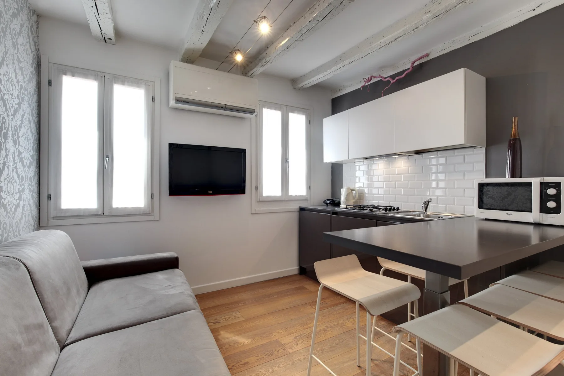 Una pequeña sala de estar con sofá, televisor y barra de cocina.