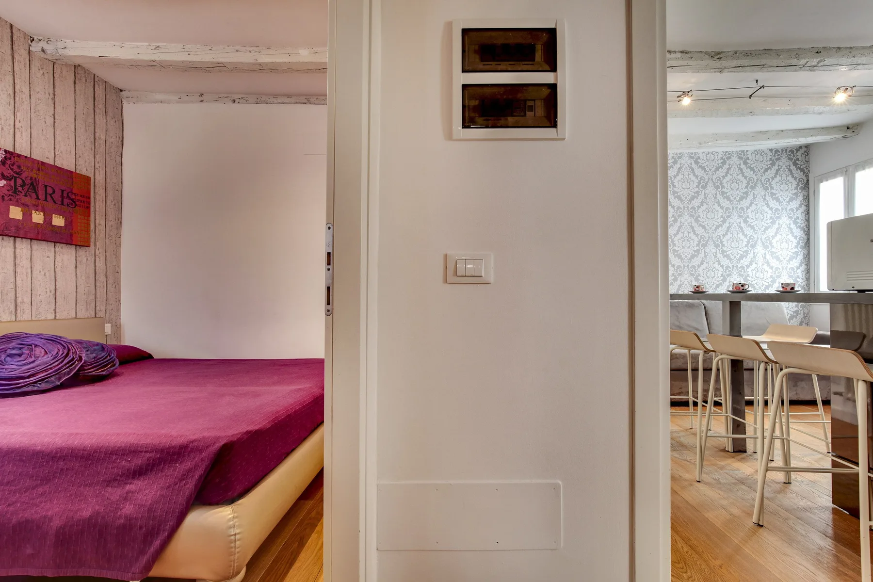Un dormitorio con una colcha magenta se abre a un comedor.