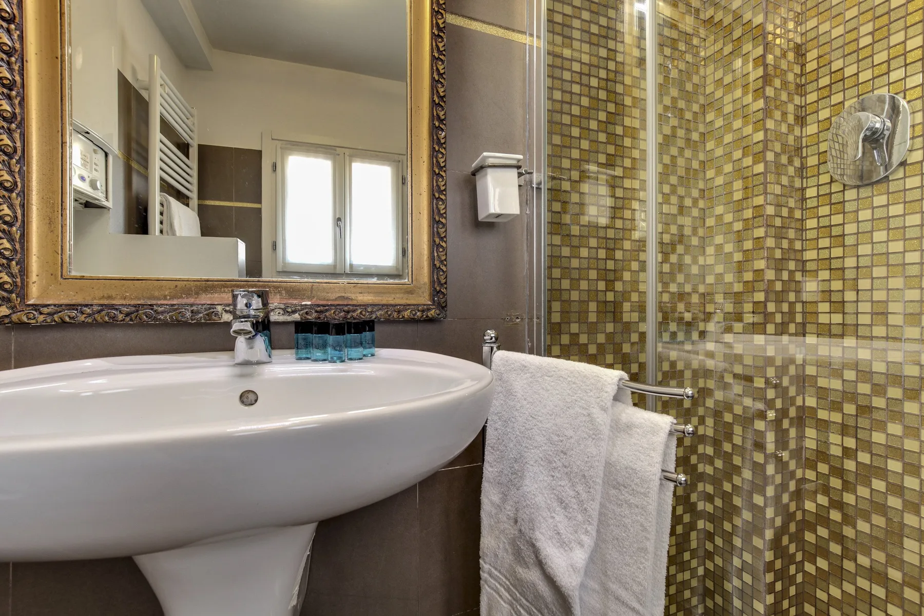 Un lavabo y un espejo están junto a una zona de ducha con azulejos.
