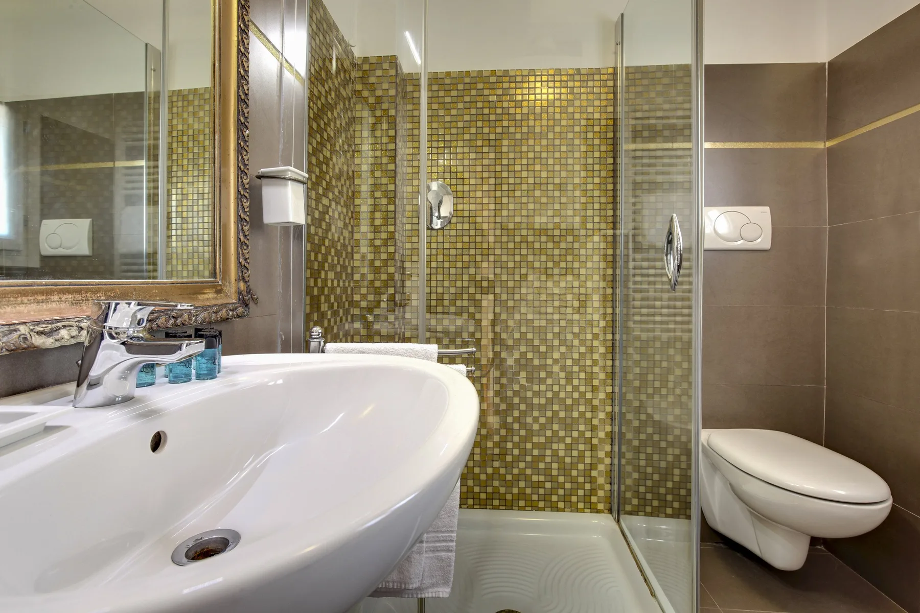 Un baño con lavabo curvo, ducha de vidrio e inodoro.