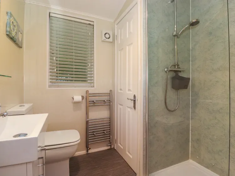A bathroom with a toilet, towel rack, and glass shower.