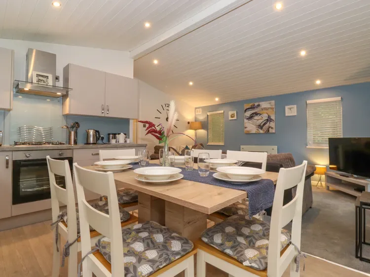 An open-plan kitchen and dining area with a wooden table and white seating.