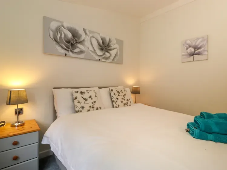 A bedroom with a neatly made bed, floral pillows, and matching wall art.