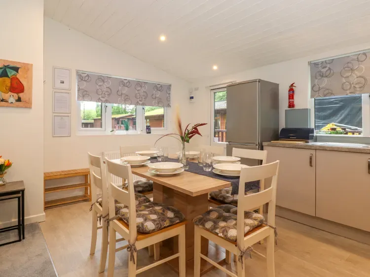A dining area with a wooden table and chairs beside a kitchen.