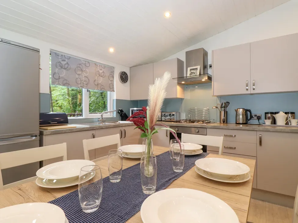 A kitchen and dining area with a set table and flowers in a vase.