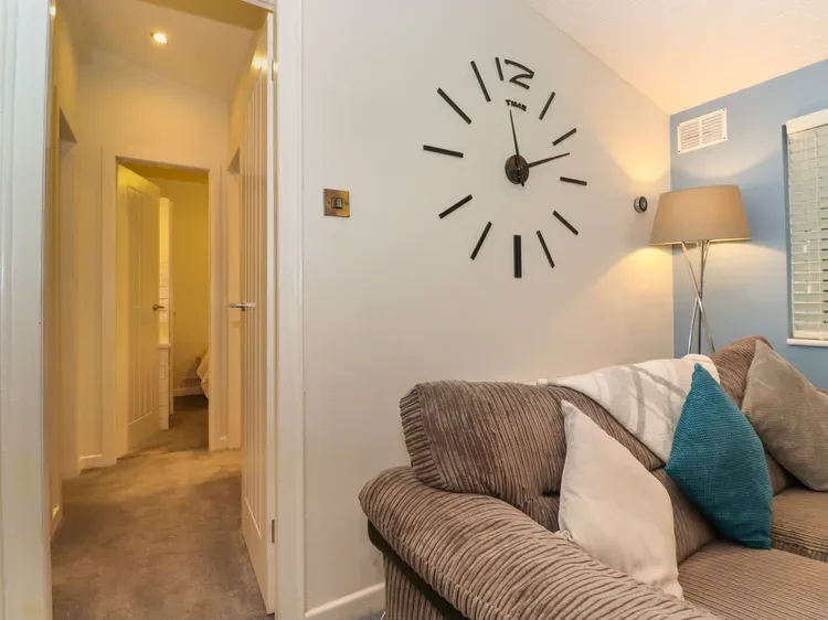 A living room with seating, pillows, and a large wall clock.