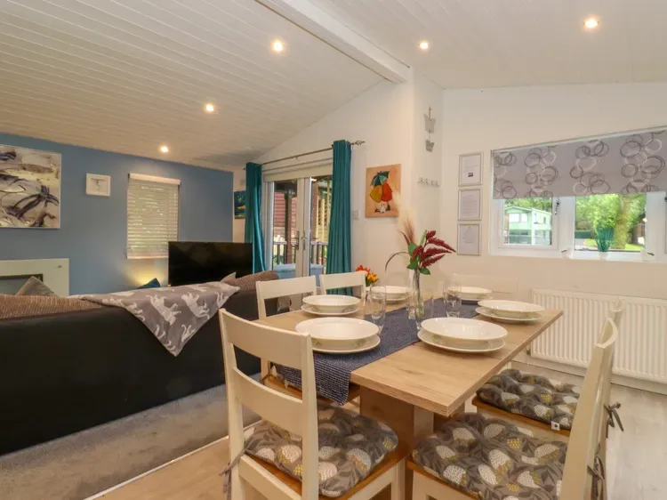 A dining area with a set table sits beside a living area with a television.